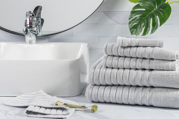 stacked folded gray towels in front of a white sink in a bathroom