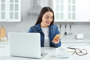 Poster - Home workplace. Woman with smartphone at marble desk in kitchen