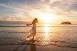 © Kittiphan - Young woman traveler dancing and enjoying beautiful Sunset on the tranquil beach, Travel on summer vacation concept