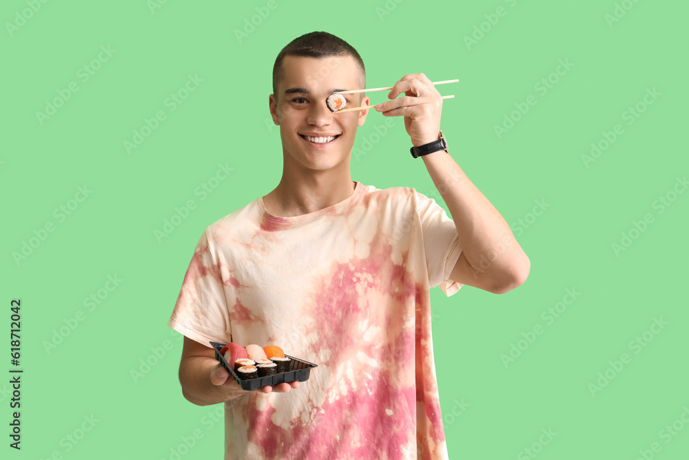Young man with tasty sushi on green background