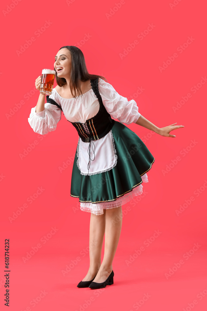 Beautiful Octoberfest waitress with beer dancing on red background