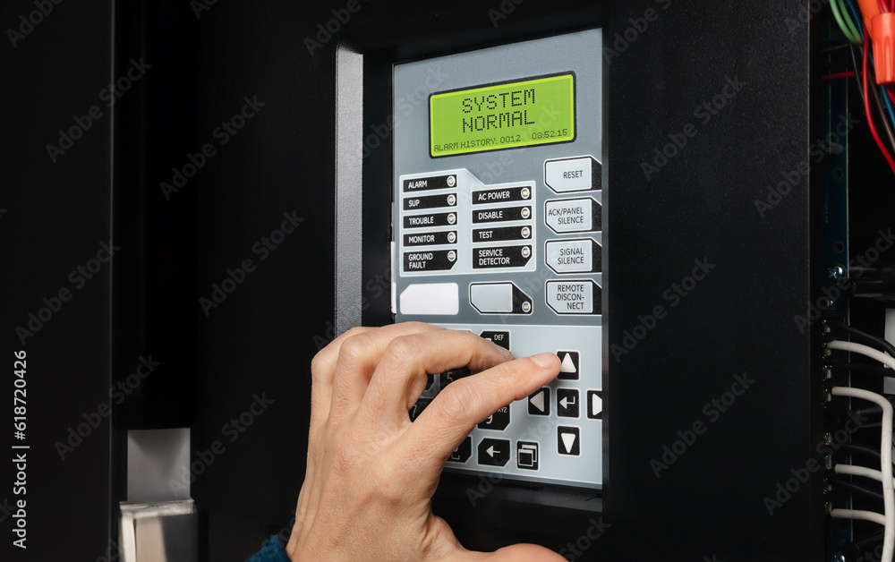 Technician using fire alarm control panel in service room. Single-stage fire alarm system in strata, residential or commercial building. Yearly checkup or trouble shooting problem. Selective focus.
