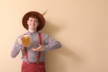 Young man in traditional German clothes with beer on beige background