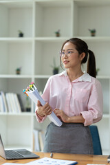 Wall Mural - Young beautiful asian businesswoman holding unofficial spreadsheet paper accounting documents Division of documents to prepare the search Summarize the plan in a meeting at the office.