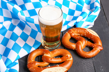 Flag of Bavaria, mug with beer and pretzels on black wooden background