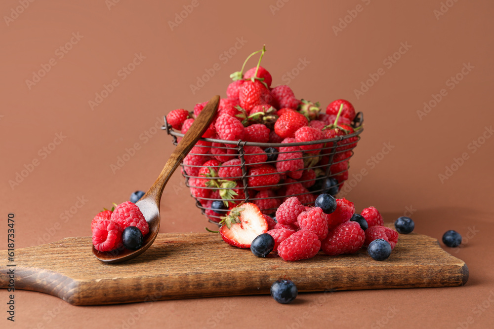 Basket with fresh raspberries, blueberries and strawberries on brown background