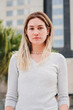 © Jose Calsina - Vertical individual portrait of blonde caucasian young adult woman looking serious at camera. Pretty teenage student girl staring front with pensive expression. Determined lady standing outside. High