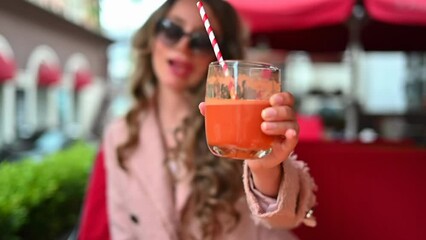 Wall Mural - Woman drinking fresh carrot juice at a restaurant terrace