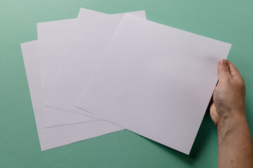 Poster - Hand of caucasian woman holding piece of paper over paper pieces with copy space on green background