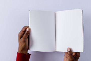 Poster - Hands of biracial man holding book with copy space on grey background