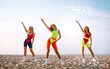 © maxbelchenko - Three young woman in bright swimsuits.  Dancing on the beach.Sport, summer, fitness, urban culture concept.