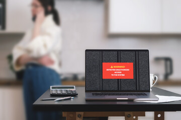 a laptop computer standing on a table with a system hacking message on the screen.