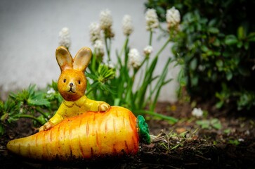 Poster - Easter bunny with a Carrot in front and flowers in background