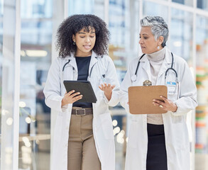 Team, tablet and documents with woman doctors walking in a hospital for insurance or healthcare discussion. Collaboration, trust and consulting with female medicine professionals talking in a clinic