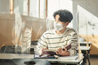 © TEAM PRE-LIGHT - A young male Asian college student is learning or listening to a lesson while her face is outside a protective shield on the desk in a university classroom in Korea during the pandemic.
