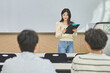 © TEAM PRE-LIGHT - A female college student in Asia is standing in front of a lecture hall at a university in South Korea, giving a presentation and lecture. The male students are sitting in front of her