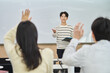 © TEAM PRE-LIGHT - An Asian young man is standing in front of a lecture hall at a university in South Korea, giving a presentation or lecture. In front of him are male and female students.
