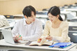 © TEAM PRE-LIGHT - In a higher education classroom in South Korea, young university students are listening to a lecture, studying, and talking. A woman and a man are in the background