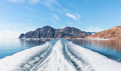 Wall Mural - fast moving motorboat trying to get out of the ice with rainbow in dense fog - stranded icebergs in 