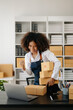 © Nuttapong punna - Small business entrepreneur SME freelance African woman working at home office, BOX,tablet and laptop online, marketing, packaging, delivery,  e-commerce concept