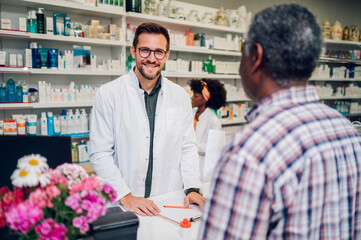 Portrait of a male pharmacist working in pharmacy and smiling while looking into the camera