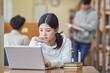 © TEAM PRE-LIGHT - Young Asian Korean female model in library looking at laptop or book, lecture, assignment, discussion, male model in background, bookshelf in background
