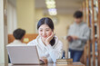 © TEAM PRE-LIGHT - Young Asian Korean female model in library looking at laptop or book, lecture, assignment, discussion, male model in background, bookshelf in background