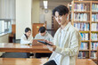 © TEAM PRE-LIGHT - Young Asian Korean male model, man and woman model and looking out the window with tablet in the library on the background of bookshelf
