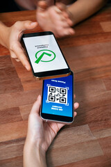 qr code is displayed on screen for cashless payment scanning. closeup hands hold smartphone to trans