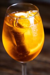 Poster - Clear glass tumbler filled with an orange liquid and ice cubes on a blurred background