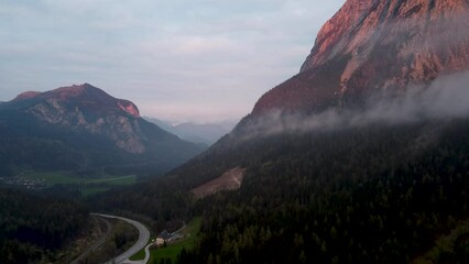 Poster - Aerial landscape view of high rocky mountains with forest trees and a road with cloudy sky