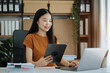 © NINENII - Women are using tablet and laptop to work at the desk in the morning.