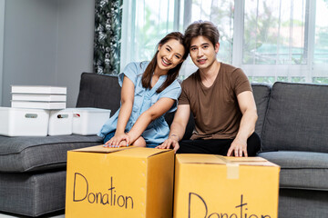 Portrait of a happy young couple packing stuff clothes, object charity in cardboard box, reused for donate, Product recycle or volunteer sharing donation concept.