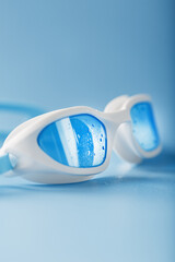 Swimming goggles in a white frame with on a blue background