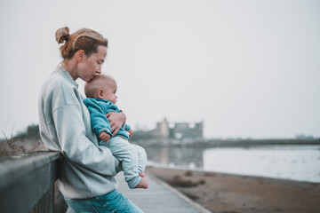 Tender woman caressing her little baby boy infant child outdoors on autumn trip to Secovlje salinas landscape park, Slovenia. Mother's unconditional love for her child