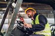 © kanpisut - Man worker at forklift driver happy working in industry factory logistic ship. Man forklift driver in warehouse area. Forklift driver sitting in vehicle in warehouse.