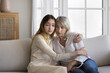 © fizkes - Sad teen granddaughter hugging depressed mature grandmother, giving support, help, comforting, consoling granny. Teenage daughter girl and middle aged mother going through family problems