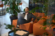 © Viacheslav Yakobchuk - Smiling male comfortably settled down with laptop in lounge area