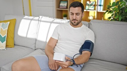 Sticker - Young hispanic man measuring pulse using tensiometer at home