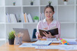 © Tj - Sharing good business news. Attractive young businesswoman Used the laptop with document and smiling while sitting at her working place in office.