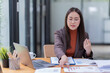© Tj - Sharing good business news. Attractive young businesswoman talking on the mobile phone and smiling while sitting at her working place in office and looking at laptop PC.