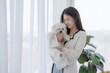 Cheerful woman in casual clothes spending her free time on vacation playing with cute pet at home.