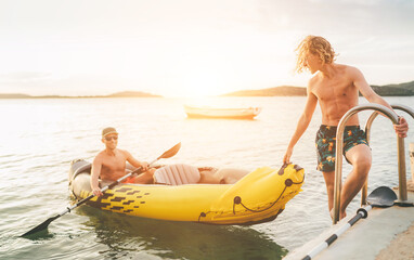 Wall Mural - Father with teenager son on the bright yellow inflatable kayak returning back from evening ride by the Adriatic sea harbor in Croatia near from Sibenik city. Vacation and family values vertical image.