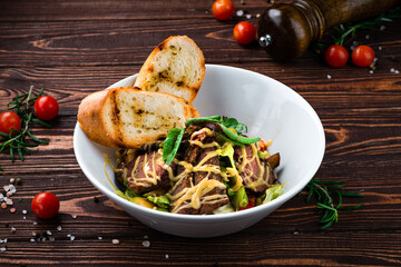 Wall Mural - Meat salad with beef slices, sweet pepper, lettuce, greens and fried toasts.