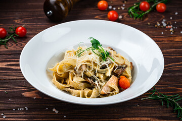 Canvas Print - Pasta Tagliatelle with chicken, tomatoes, mushrooms, parmesan cheese and greens in a plate.