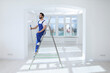 © New Africa - Handyman with roller on step ladder in room. Ceiling painting