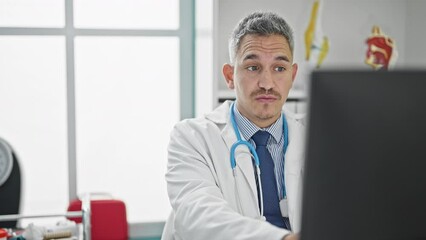 Sticker - Young hispanic man doctor using computer having medical consultation at clinic