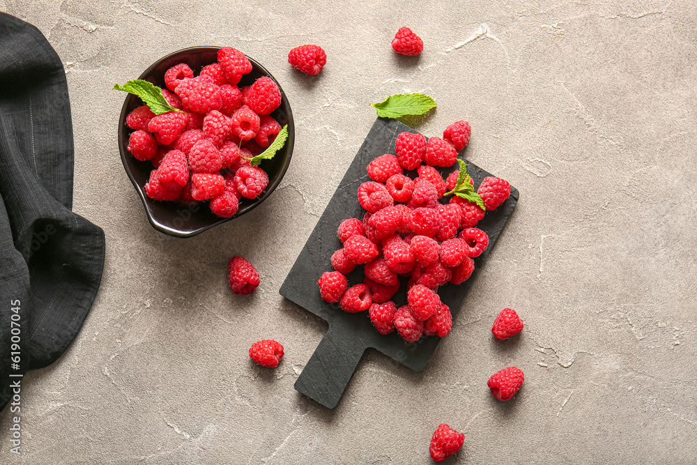 Board and bowl with fresh raspberries on grey table