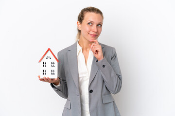 Wall Mural - Real estate agent woman holding a toy house isolated on white background and looking up