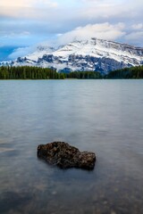 Sticker - Picturesque Two Jack lake surrounded by majestic snowy mountains and lush green trees